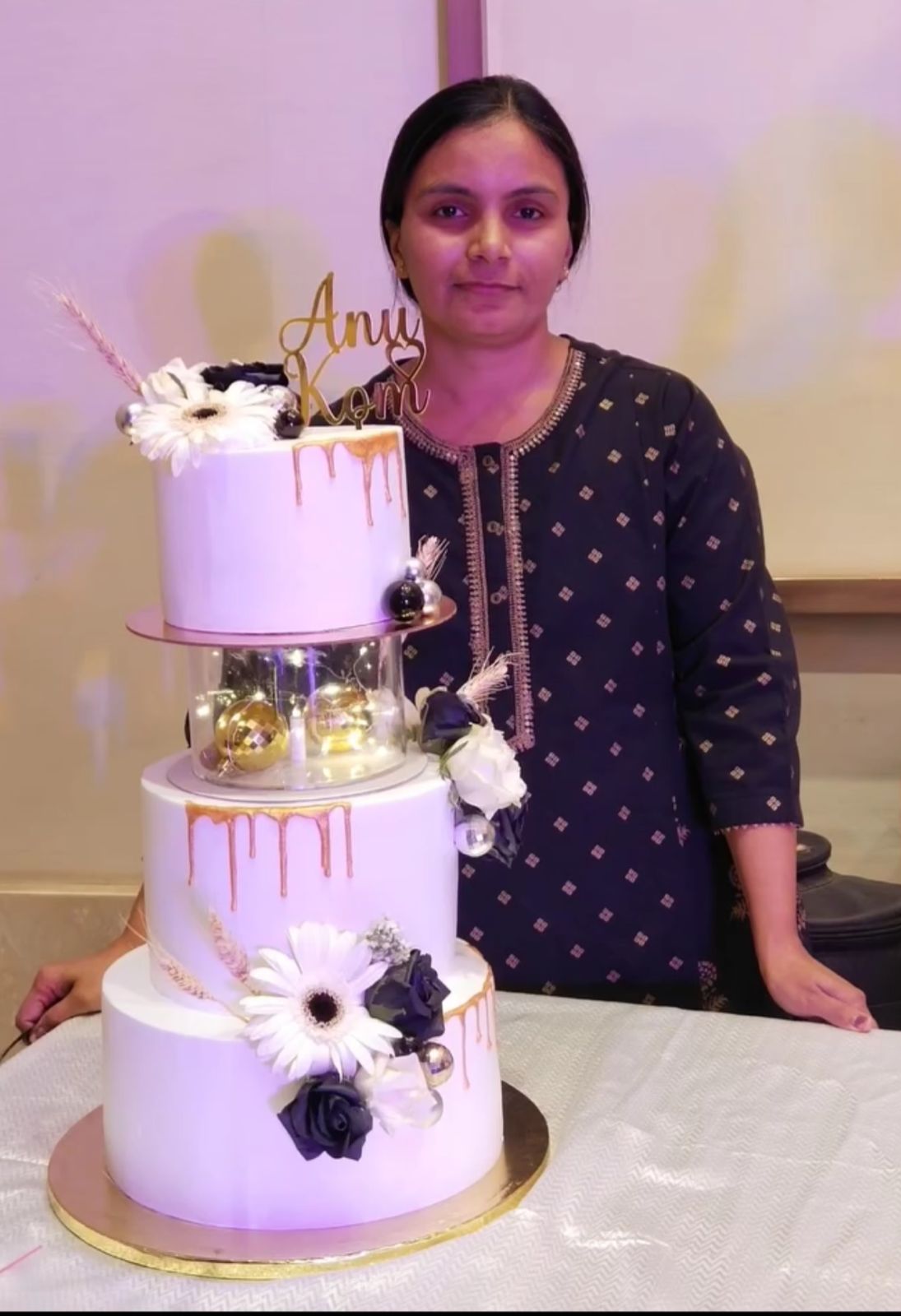 Kirti with a beautiful three-tier cake, representing her artistry and dedication to custom cake design